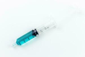 Medical syringe with blue liquid inside on white background with copy space for your text. photo