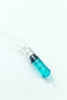 syringe with blue liquid inside on white background. Isolated photo