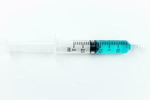 Medical syringe with blue liquid inside on a white background. Isolated with clipping path. photo