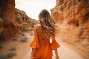 AI generated a beautiful girl wearing orange dress walking trough the desert canyon photo