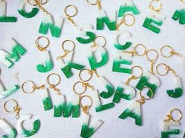 Resin key chain made of green and gold chain on white background. Flat lay, top view. photo