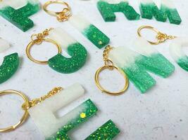 Resin key chain made of green and gold chain on white background. Flat lay, top view. photo