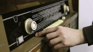 Close-up of man's hand rotating the knob on the old radio. Concept. Vintage technology photo