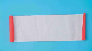 An orange rolled square paper is spread out into a blank white sheet on a light blue background. Crumpled blank white paper with copy space for text or advertising space. video