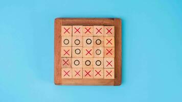 Wooden game board tic-tac-toe. Turning of the letters X-O and middle one different from each other on blue background. video