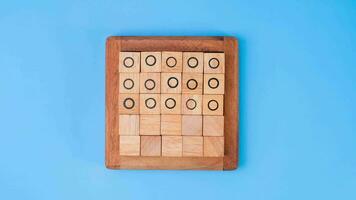 Wooden game board tic-tac-toe. Turning of the letters X-O and middle one different from each other on blue background. video