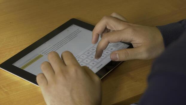 Close-up of male hands using modern digital tablet and computer at office, frontal view of businessman hands typing text information on touch screen of tablet pc photo