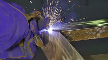 Metal Welding with sparks and smoke. Worker with protective mask welding metal. Welder joins metal parts. A process using a semi-automatic welding. Welding steel. Industrial Worker at the factory photo