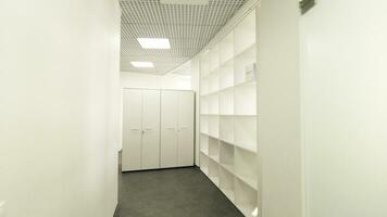 Long, arcuate office hallway and a reception desk. Corridor of a public building with chairs near walls and many doors. photo