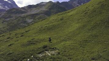 Aerial view of a man riding a horse on a green moountain slope. Clip. Beautiful summer day, mountain range, cloudy sky and green fresh grass covering the hill. photo