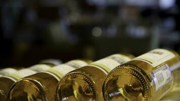 Blurred bottles of white and rose wine are nicely laid out in a row on a shelf in a large supermarket. Bright abstract background ideal for any design. Rack in wine cellar with resting bottles photo