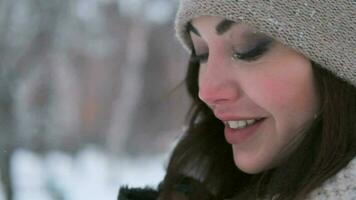 portrait of a beautiful girl with blue eyes and dark hair posing in a winter park in a good mood. close-up video