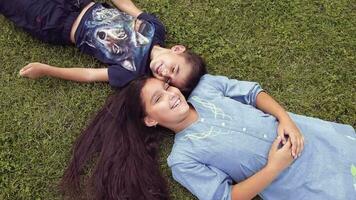 A Little boy with a girl having fun lying on the grass. On a summer sunny day. Brother and sister video