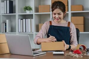 Startup small business entrepreneur SME, asian woman packing cloth in box. Portrait young Asian small business owner home office, online sell marketing delivery, SME e-commerce telemarketing concept photo