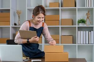 Startup small business entrepreneur SME, asian woman packing cloth in box. Portrait young Asian small business owner home office, online sell marketing delivery, SME e-commerce telemarketing concept photo