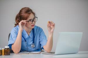 Young Asian doctor in a white medical uniform with a stethoscope using a lab computer and tablet to organize and classify medicines in preparation for administration to patients. photo