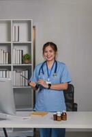 Young asian 30s female medic in uniform holding clipboard in doctor's office photo