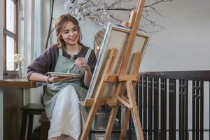 Young female artist works on abstract acrylic painting on canvas in art painting studio. photo