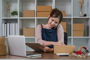 Startup small business entrepreneur SME, asian woman packing cloth in box. Portrait young Asian small business owner home office, online sell marketing delivery, SME e-commerce telemarketing concept photo