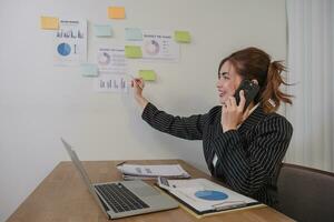 Asian businesswoman in a formal suit in the office is happy and cheerful while using a smartphone to work in her office. photo
