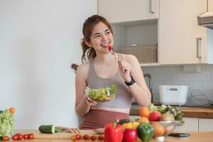 Sporty young woman is preparing healthy food on light kitchen. healthy food concept. photo