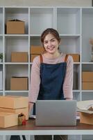 Portrait of Asian young woman SME working with a box at home the workplace.start-up small business owner, small business entrepreneur SME or freelance business online and delivery concept. photo