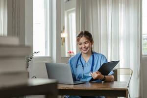 joven asiático dama médico en blanco médico uniforme con estetoscopio utilizando computadora ordenador portátil hablando vídeo conferencia llamada con paciente a escritorio en salud clínica o hospital. foto