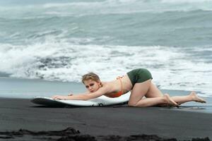 Amazing surfer striking sensuality pose with their trusty surfboard on sandy beach of Pacific Ocean photo