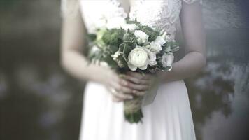 Beautiful bouquet of different colors in the hands of the bride in a white dress. Bride in white dress with bouquet. Woman holds wedding bouquet. Wedding photo