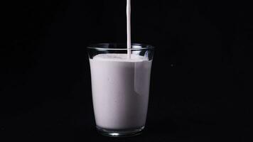 Close-up of clean glass filled by strawberry milkshake. Frame. Isolated on black photo
