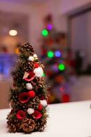 Close up of christmas tree in festive kitchen organized for winter dinner festivity. Nobody in empty bright room with illuminated garland ornaments, cooking utensils and wooden interior photo