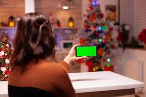 Young woman holding smartphone with green screen for virtual technology on mockup template. Caucasian person analyzing digital device with chroma key to view background design concept photo