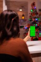 Young woman holding smartphone with green screen for virtual technology on mockup template. Caucasian person analyzing digital device with chroma key to view background design concept photo