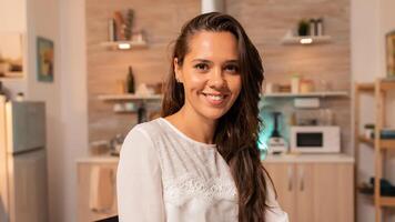 Cheerful freelancer woman smiling doing overtime to finish deadline for client. Concentrated entrepreneur in home kitchen using notebook during late hours in the evening. photo