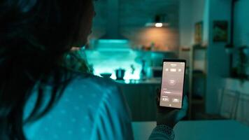 Woman using automation phone app to change light color remotely. Person in apartment holding telephone with touchscreen and app for lights. photo