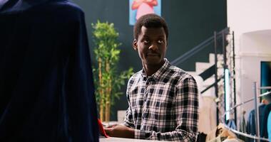 Portrait of customer smiling during shopping session, analyzing elegant tie in modern boutique. African american man shopping for stylish merchandise and trendy accessories in clothing store photo