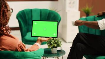 Tourists in hotel lobby being assisted by manager, holding chroma key green screen mock up tablet in landscape mode. Resort administrator helping guests during check in process photo