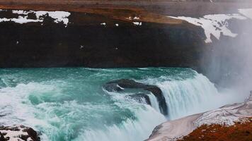 Majestic water stream in iceland with snowy nature and hills, gullfoss waterfall in reykjavik. Beautiful large river flow cascade with scandinavian nordic landscapes. Handheld shot. photo