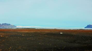 Beautiful countryside scenery with field and white snowy mountains on roadside, scandinavian landscapes with frozen hills. Fantastic icelandic nature with panoramic view. Handheld shot. photo