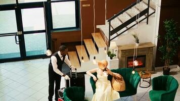 Hotel concierge carrying baggage for tourist, helping with trolley bags in reception lobby. Bellboy working in luxury tropical resort to give assistance to guests, summertime holiday. photo