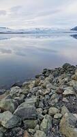 Frosty open water and snowy slopes in icelandic setting, scandinavian frozen lake within nordic iceland landscape. Majestic scenery with rock formations and ice fragments. photo