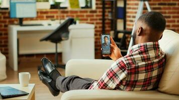 Man checking up on abroad living friend during video conference meeting over the internet. African american mates enjoying time together in online video call session while at home photo