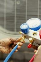 Close up of professional worker holding pressure indicators used for checking air conditioner freon tank in need of maintenance. Licensed serviceman using manifold gauges to check refrigerant levels photo