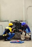 Trained engineers commissioned for yearly air conditioner maintenance, using dusting brush to clean dirty, clogged air filters restricting airflow and reducing unit ability to cool air effectively photo