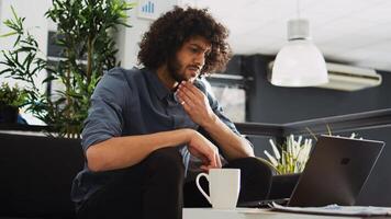 Creative employee looking to develop program in open floor plan office, working with past annual statistics to create new development strategy. Businessman thinks about startup growth. photo