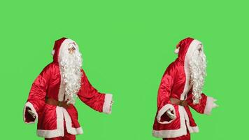 Model in santa claus suit with beard feeling positive about festive season, celebrating christmas eve holiday over greenscreen background. Joyful man advertising december celebration. photo