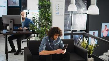 Manager taking notes on smartphone, trying to create new research project in company office. Businessman analyzing programming statistics to make decision, coworking space. photo
