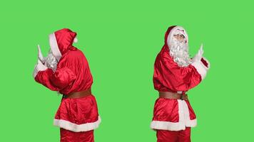 Saint nick pushing object left or right, pretending to refuse something against isolated greenscreen background. Young adult in santa festive costume doing rejection symbol aside. photo
