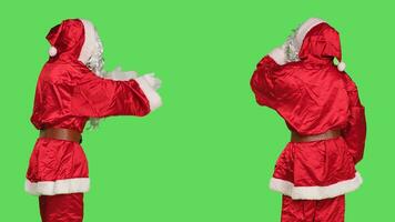 Papa Noel cosplay dando aire Besos en cámara, haciendo dulce gesto terminado pantalla verde antecedentes en estudio. joven adulto en rojo disfraz interino coqueta y romántico con alguien, Navidad víspera. foto
