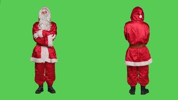 Saint nick laughing on camera, posing in red costume over full body greenscreen. Santa cosplay spreading christmas eve holiday spirit, portraying famous winter character with hat and glasses. photo